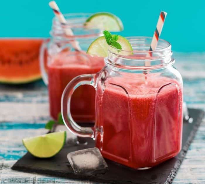 how to make a smoothie with frozen fruit, two jars, lime slices on the ...