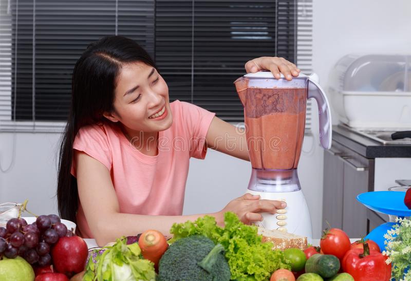 Woman Making Smoothies With Blender In Kitchen Stock Photo